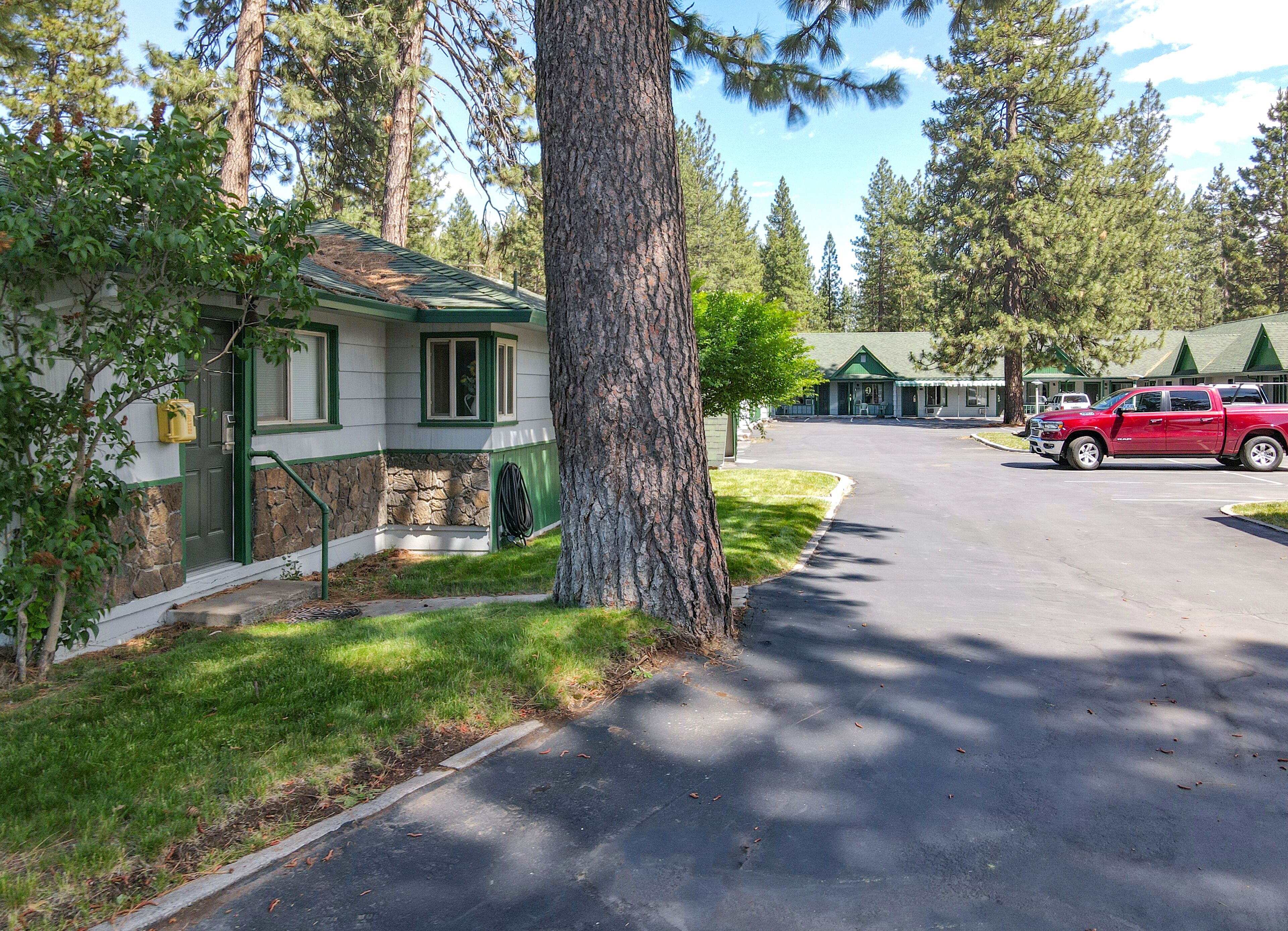 A lodge with a stone foundation, green trim, and a red truck parked in front.