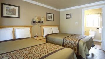 A hotel room with two beds, a nightstand with lamps, and a door leading to the bathroom.