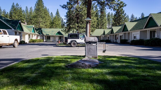 A motel with multiple rooms, a parking area, and a truck. - Green Gables Motel & Suites (Burney)