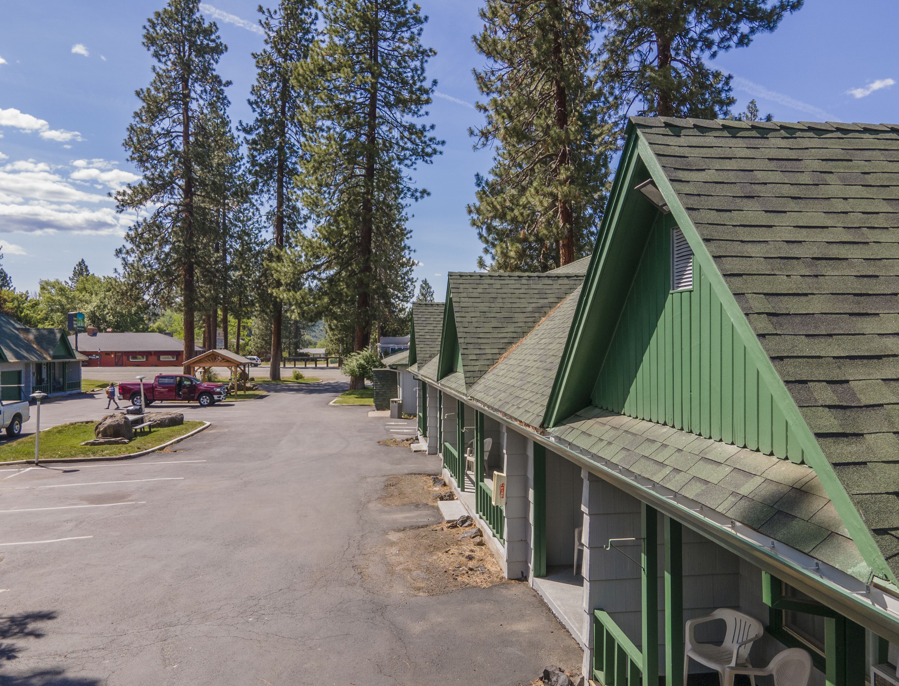 Une rangée de cabanes aux toits végétalisés, avec un parking devant.