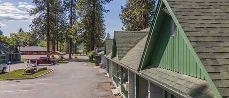 Une rangée de cabanes aux toits végétalisés, avec un parking devant.