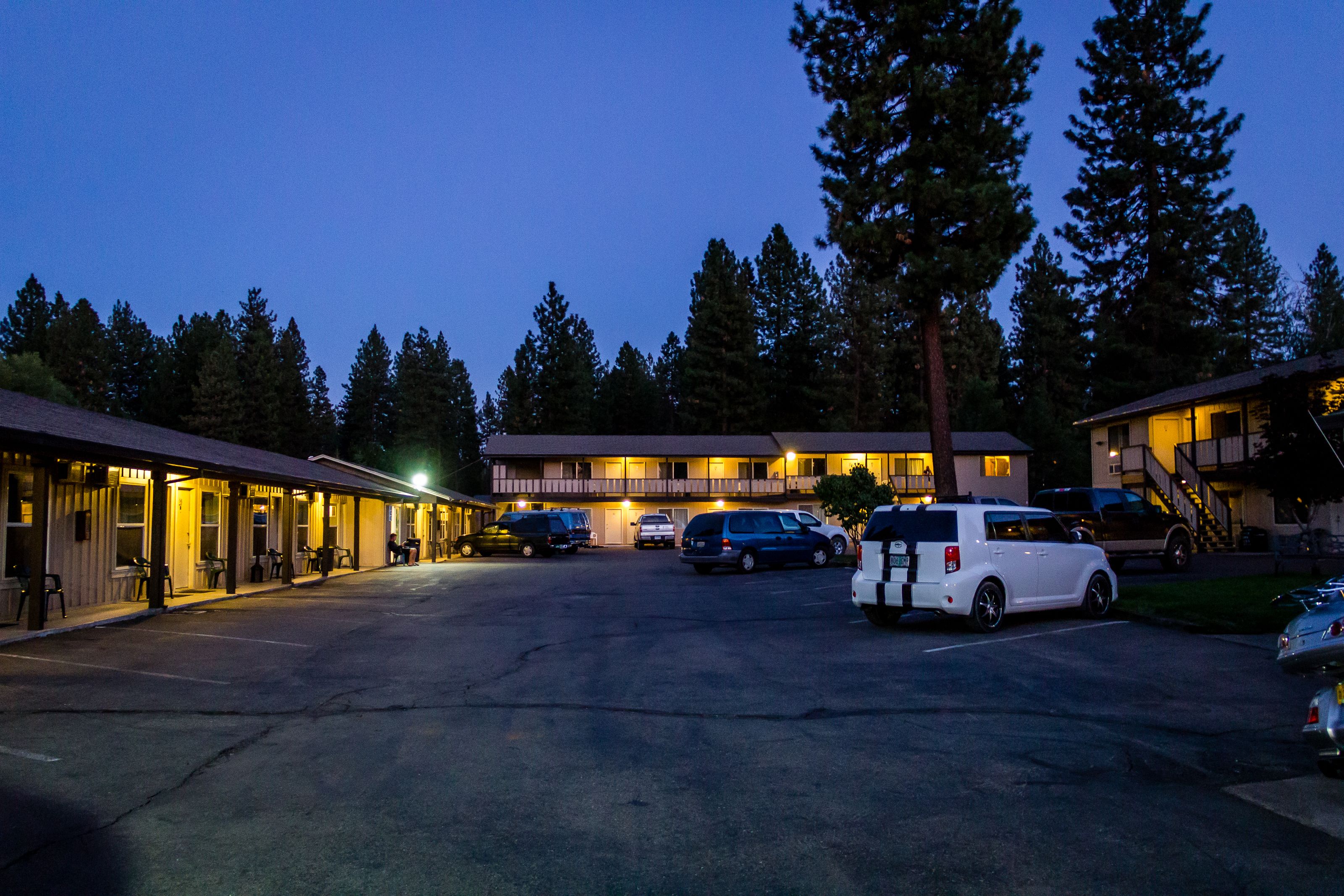 Un motel con diverse camere, un parcheggio e alcune auto parcheggiate.