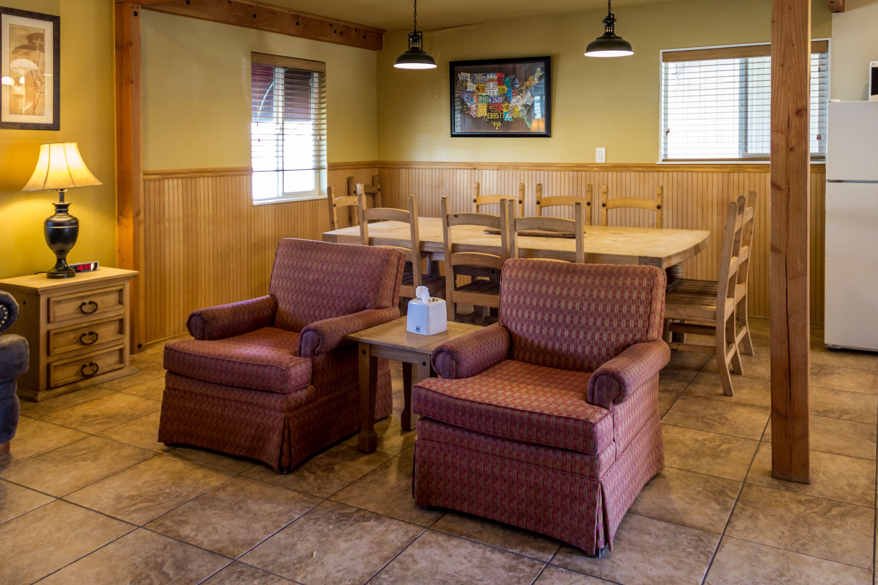 A dining area with wooden paneling, a table, chairs, and a lamp.