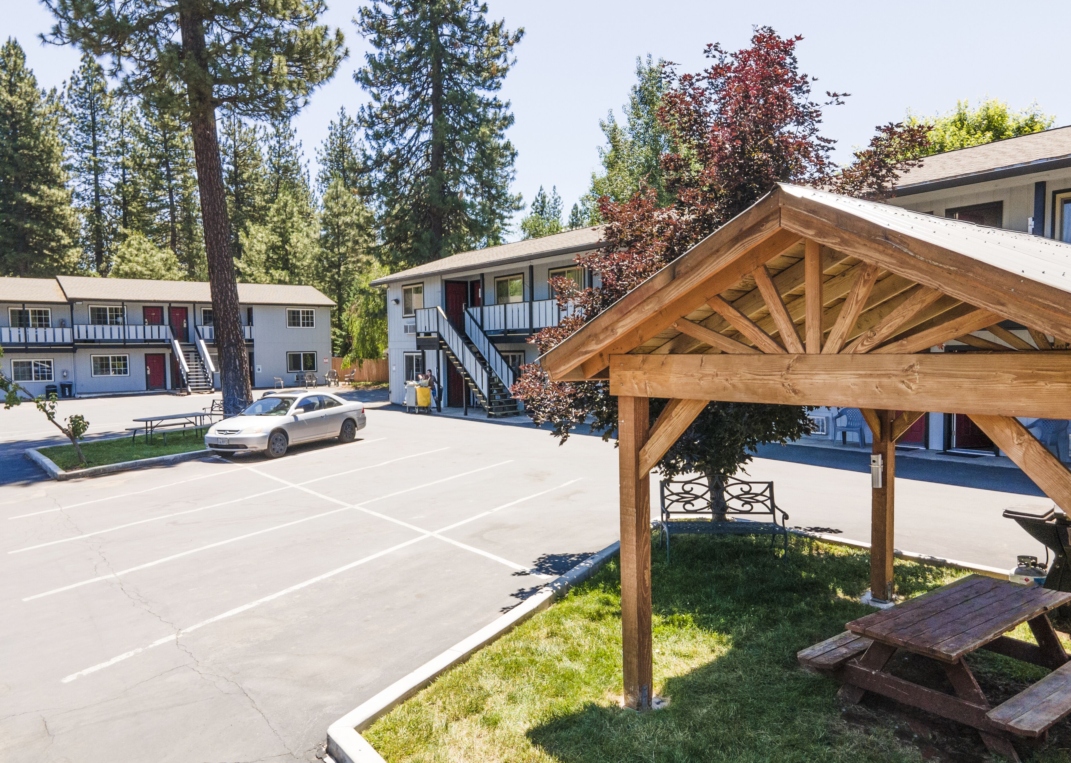 A motel with a covered picnic area, a parking lot, and a car parked in front.