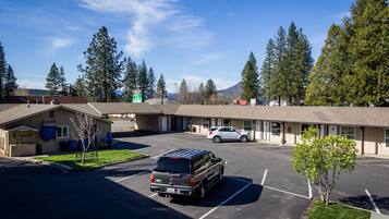 A motel with a parking lot, a small building with a covered area, and a mountain in the background.