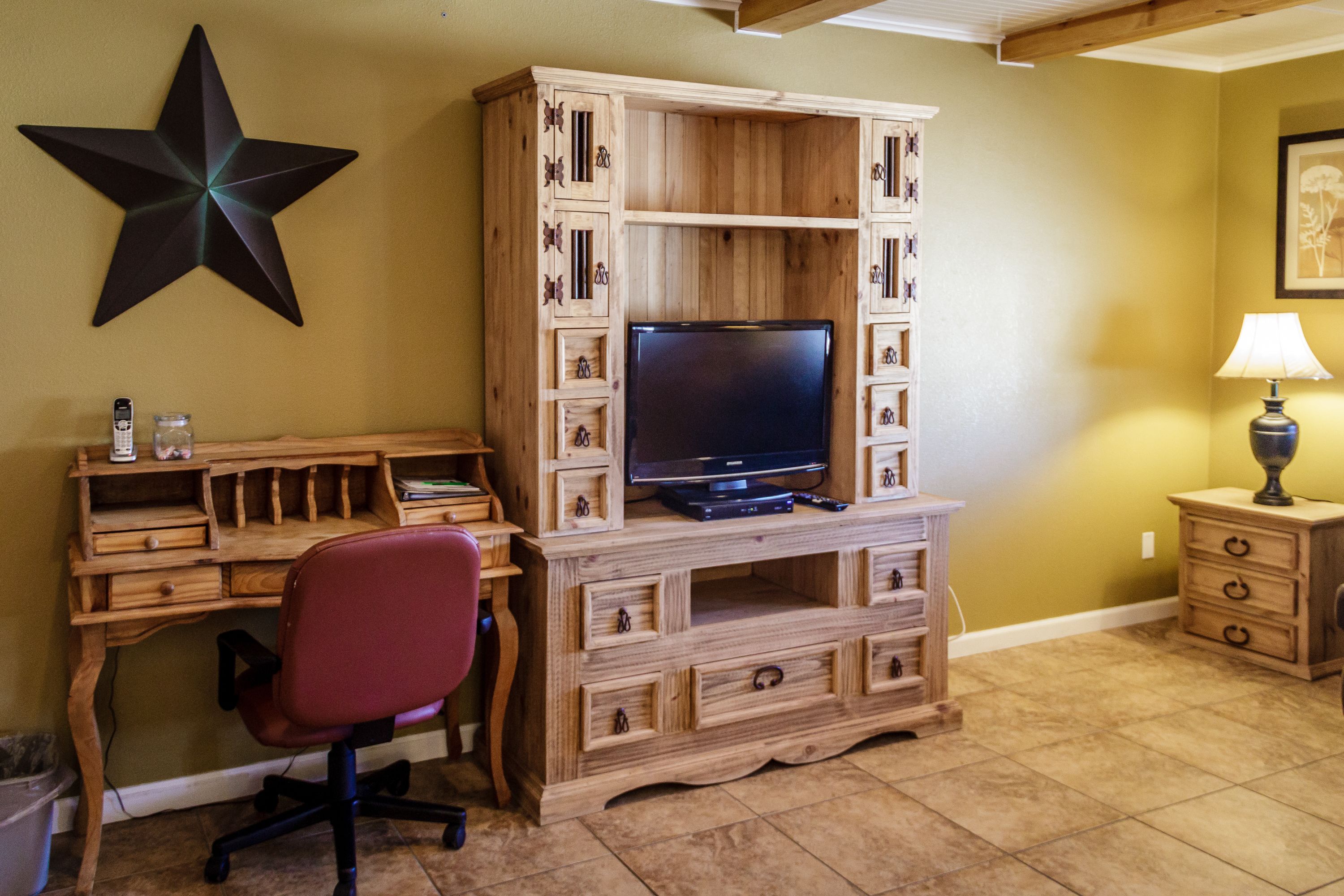 Un mueble de madera para entretenimiento con un televisor, una silla de oficina roja y una decoración de estrella en la pared.