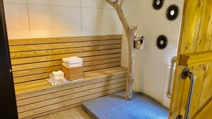 A wooden bench with towels and a decorative tree branch in a spa area. - Aitabi Hostel (Tainan)