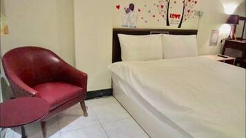 A bedroom with a large bed, a red chair, and a wall decoration featuring hearts and a tree with the word "LOVE".