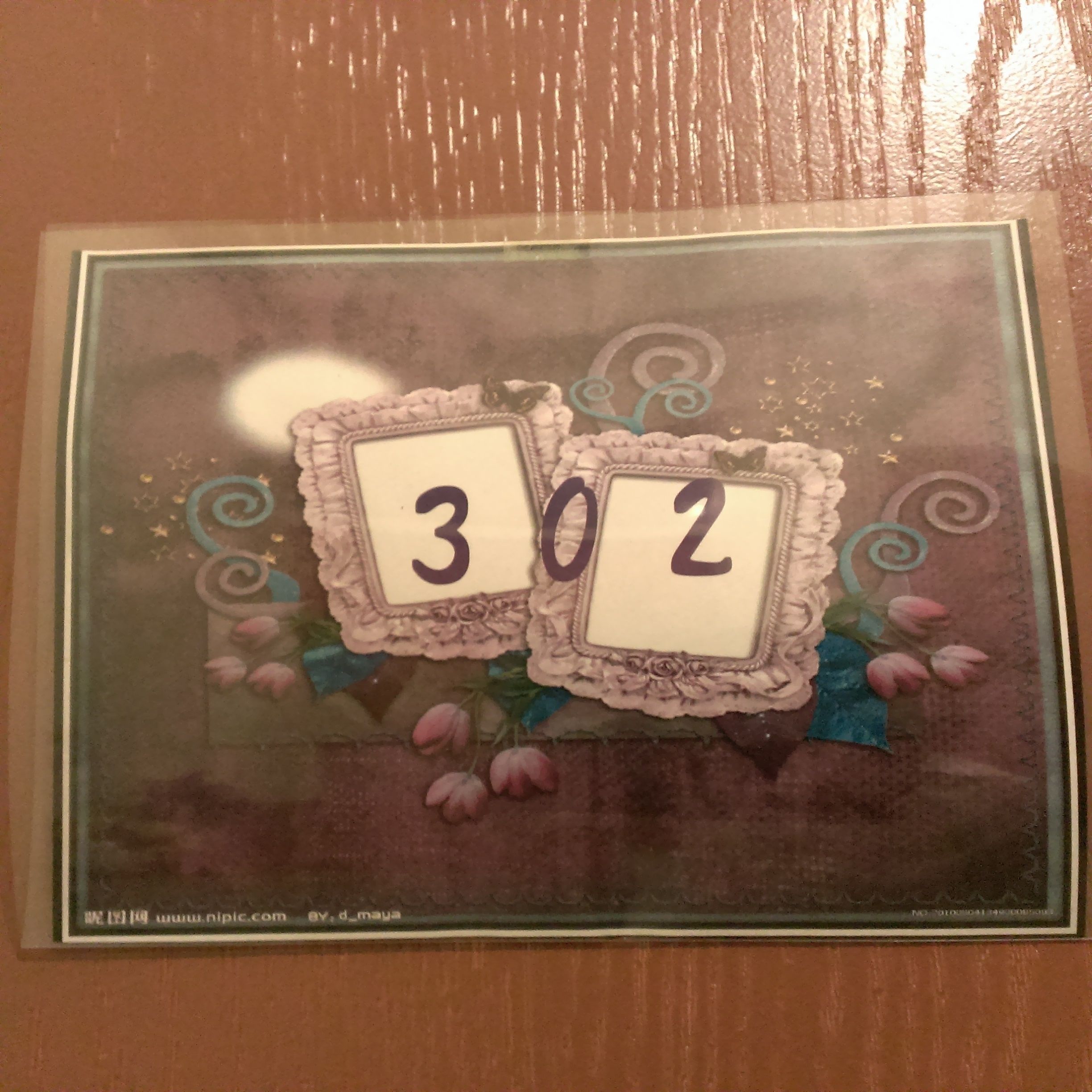 A framed picture with the numbers "302" on it, surrounded by decorative elements like swirls and flowers.