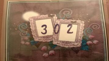 A framed picture with the numbers "302" on it, surrounded by decorative elements like swirls and flowers.