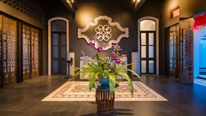 A lobby with a decorative plant centerpiece, a patterned floor, and traditional architectural elements. - Little Nyonya Hotel (Wichit)