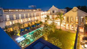 A hotel with a pool area, multiple balconies, and a well-lit courtyard. - Little Nyonya Hotel (Wichit)