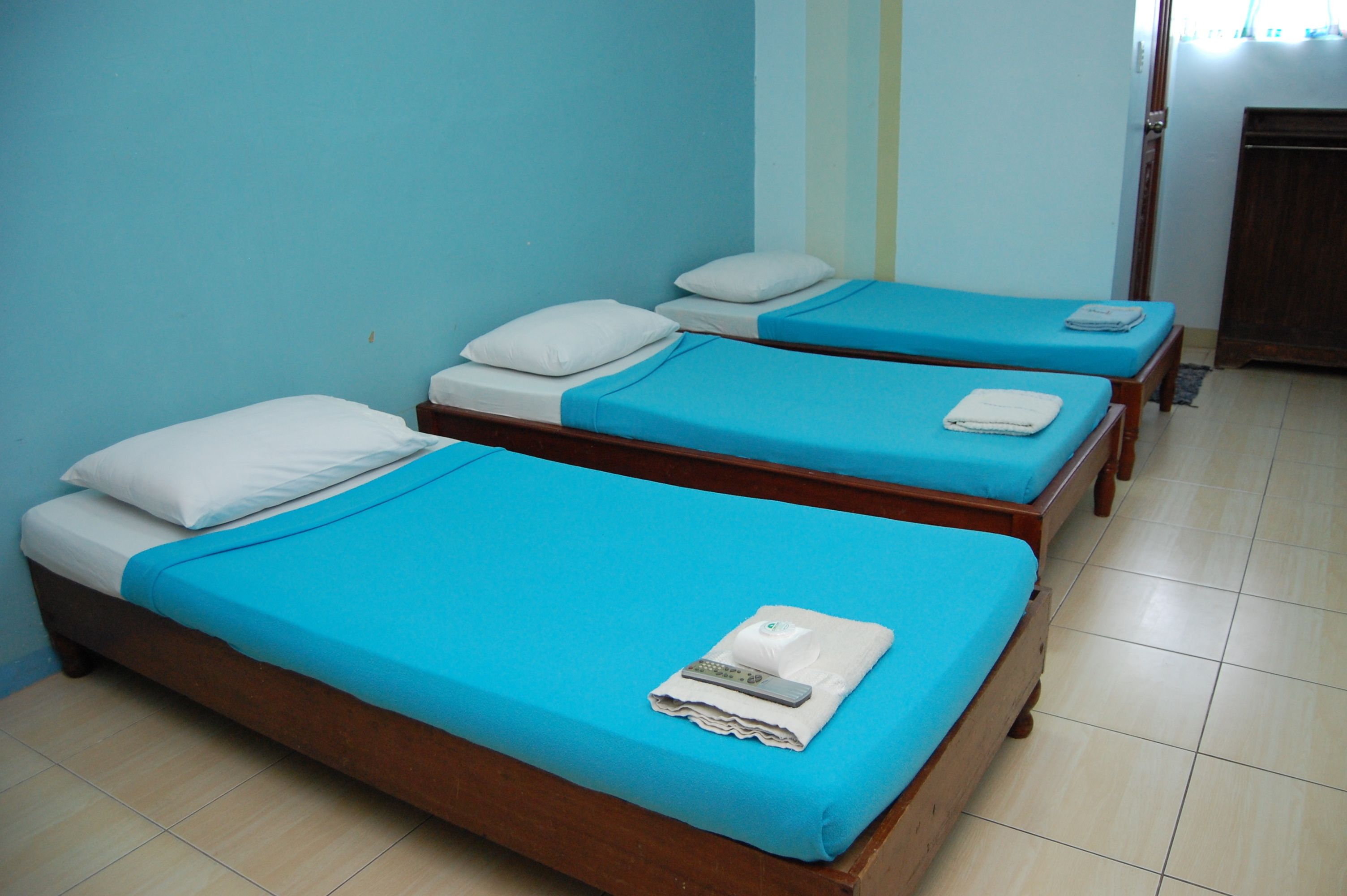 A room with two wooden beds, each with a blue mattress and white pillows.