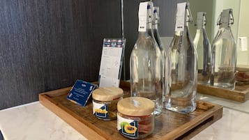 Una bandeja de madera con frascos de aperitivos, un menú y botellas de vidrio vacías sobre una encimera de mármol.
