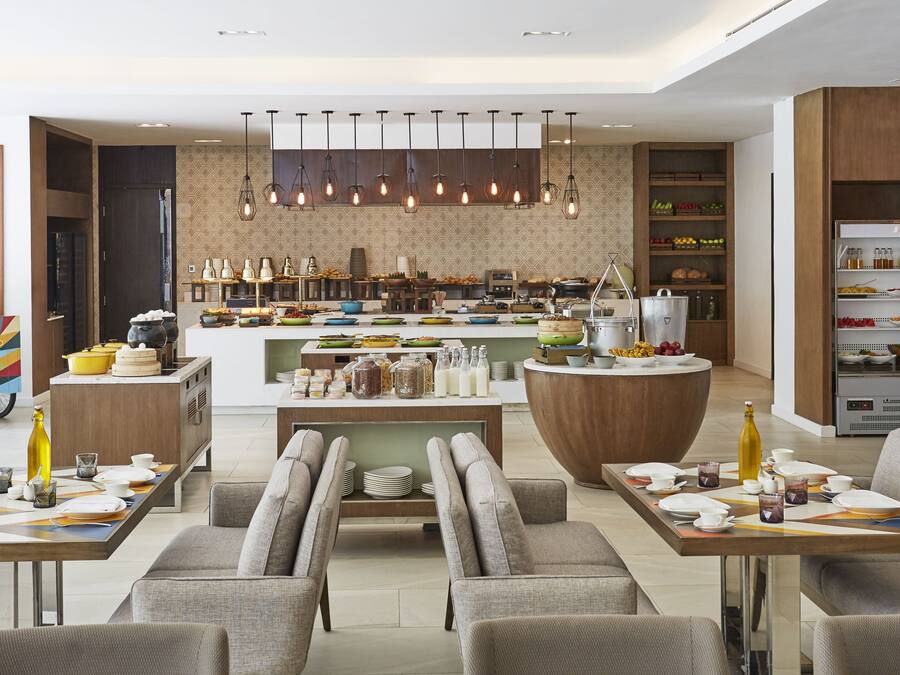 Cozinha moderna com ilha central, área de refeições com sofás e diversos eletrodomésticos e utensílios.