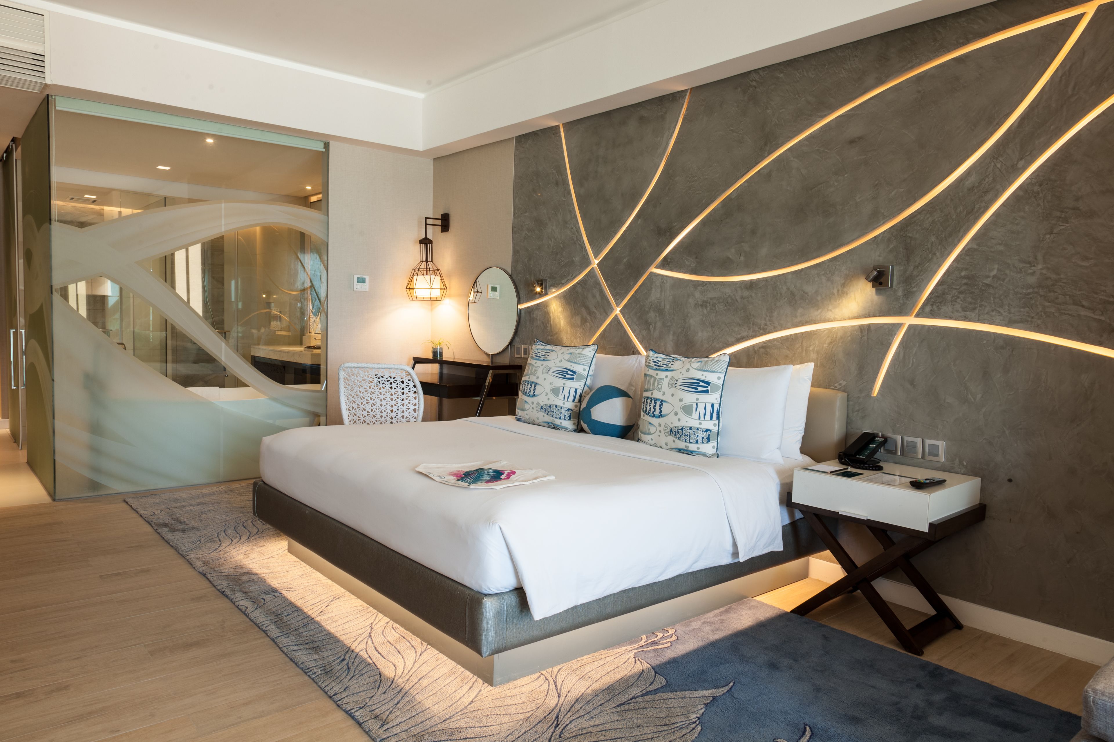 A modern bedroom with a large bed, bedside tables, and a glass wall leading to a staircase.