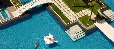 A swimming pool with a diving board, a lifeguard chair, and a palm tree.
