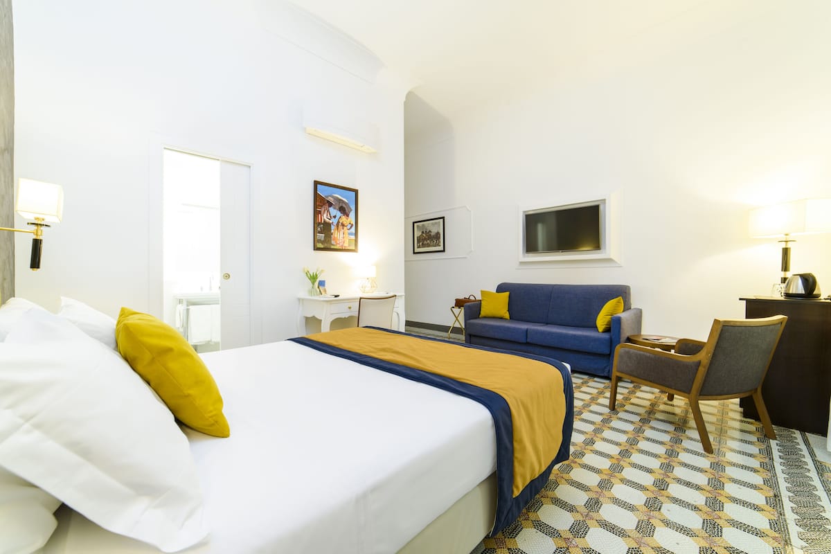 Ein Hotelzimmer mit einem Bett, einer Couch, einem Schreibtisch und einem Stuhl.