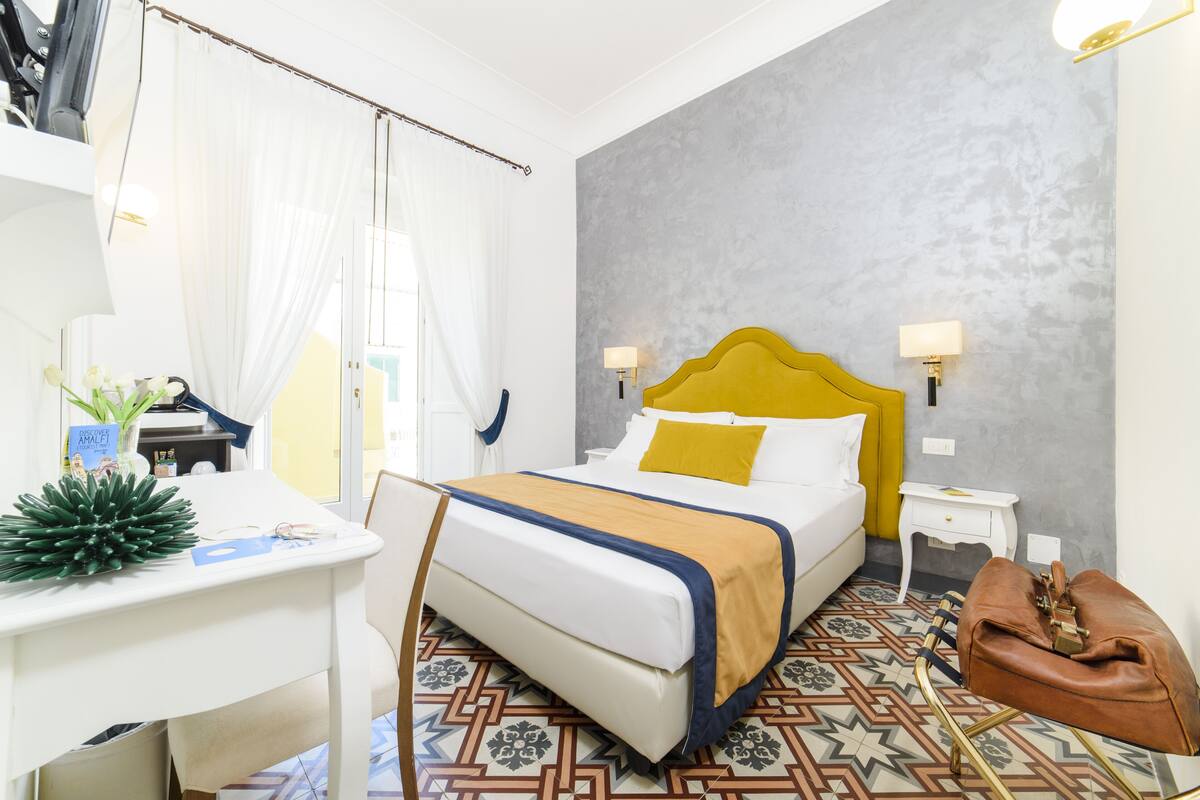 Ein Hotelzimmer mit Bett, Nachttischen, einem Schreibtisch und einem Stuhl.