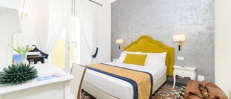 A hotel room with a bed, bedside tables, a desk, and a chair.