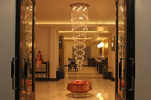 A lobby with a reflective floor, a central decorative light fixture, and a seating area with chairs and tables. - Hotel Harmika (Kathmandu)