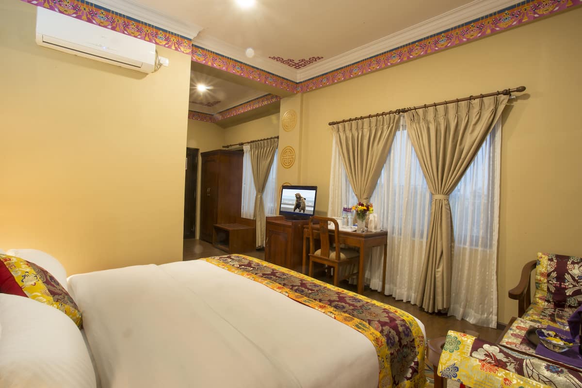 Una habitación de hotel con una cama grande, un escritorio con una computadora y una silla.