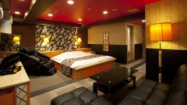 A hotel room with a bed, a massage chair, a desk, a sofa, and a lamp. - Hotel Dessert Hills - Adults only (Kyoto)