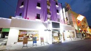A purple building with a sign that reads "Desert Hills." There are several posters on the sidewalk in front of the building. - Hotel Dessert Hills - Adults only (Kyoto)