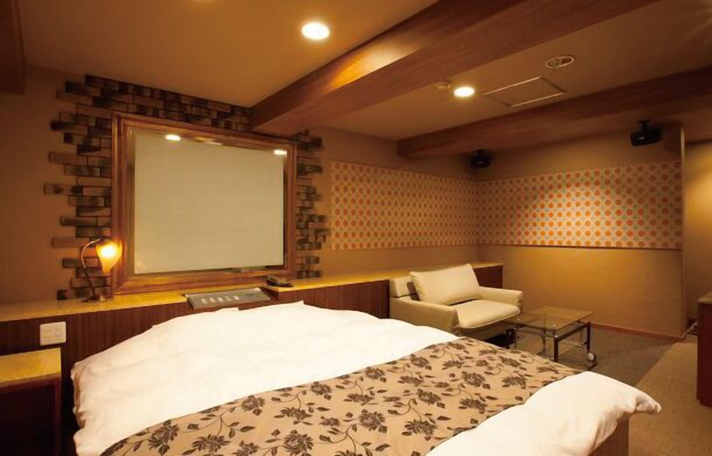 Habitación de hotel con una cama grande, un escritorio con computadora, una silla y una mesita.