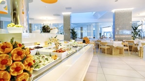 A buffet area with various food options and a seating area with tables and chairs. - Bull Escorial & Spa (San Bartolomé de Tirajana)