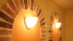 Pared de ladrillo con un espejo circular y dos luces fijadas a la pared.