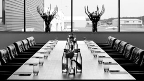 Une salle de conférence avec une longue table, des chaises et des vases remplis de fleurs.