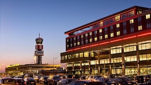 Un terminal d’aéroport doté d’une tour de contrôle, de plusieurs niveaux et d’un parking rempli de voitures.
