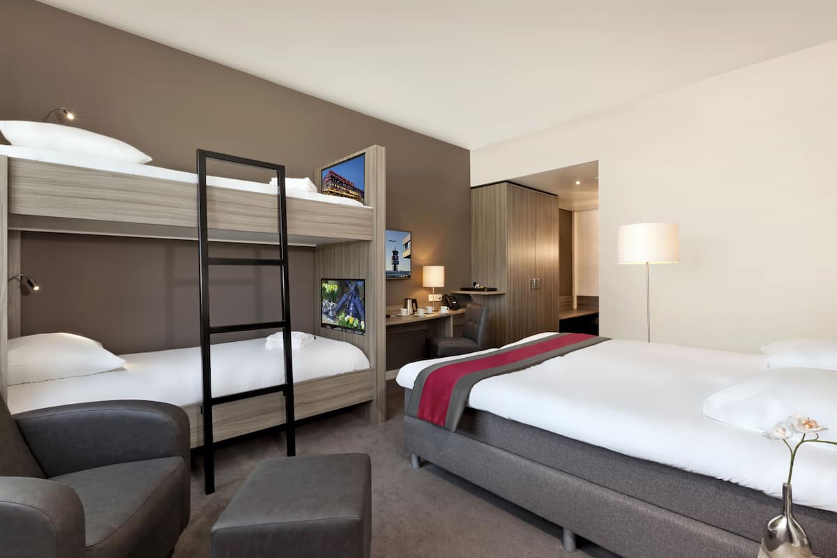 Ein Hotelzimmer mit zwei Betten, einem Schreibtisch, einem Stuhl und einer kleinen Couch.