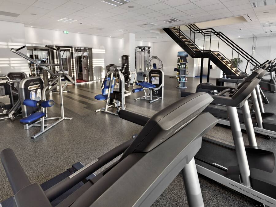 Academia moderna com diversos equipamentos de exercícios, incluindo esteiras e aparelhos de musculação.