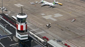 Ett kontrolltorn på flygplatsen med fri sikt över landningsbanan, inklusive parkerade flygplan och markfordon.