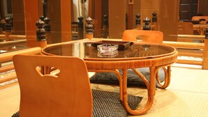A round glass table with a woven chair and matching cushions. - Hotel Parco - Adults only (Kyoto)