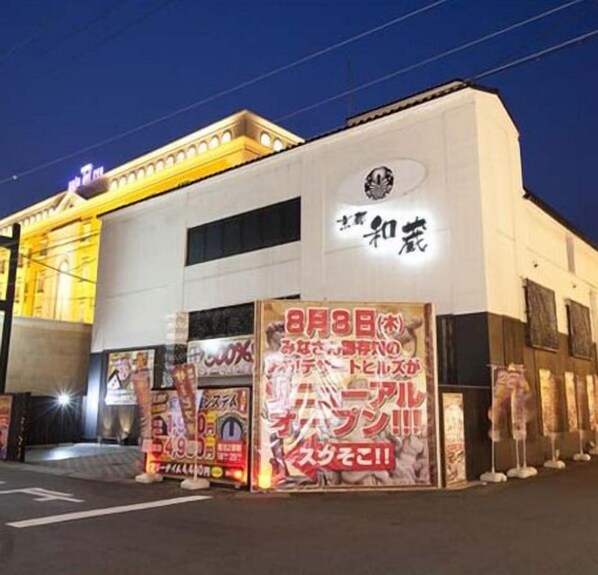 A building with a white facade and a sign with Japanese characters. There are posters on the ground in front of the building.