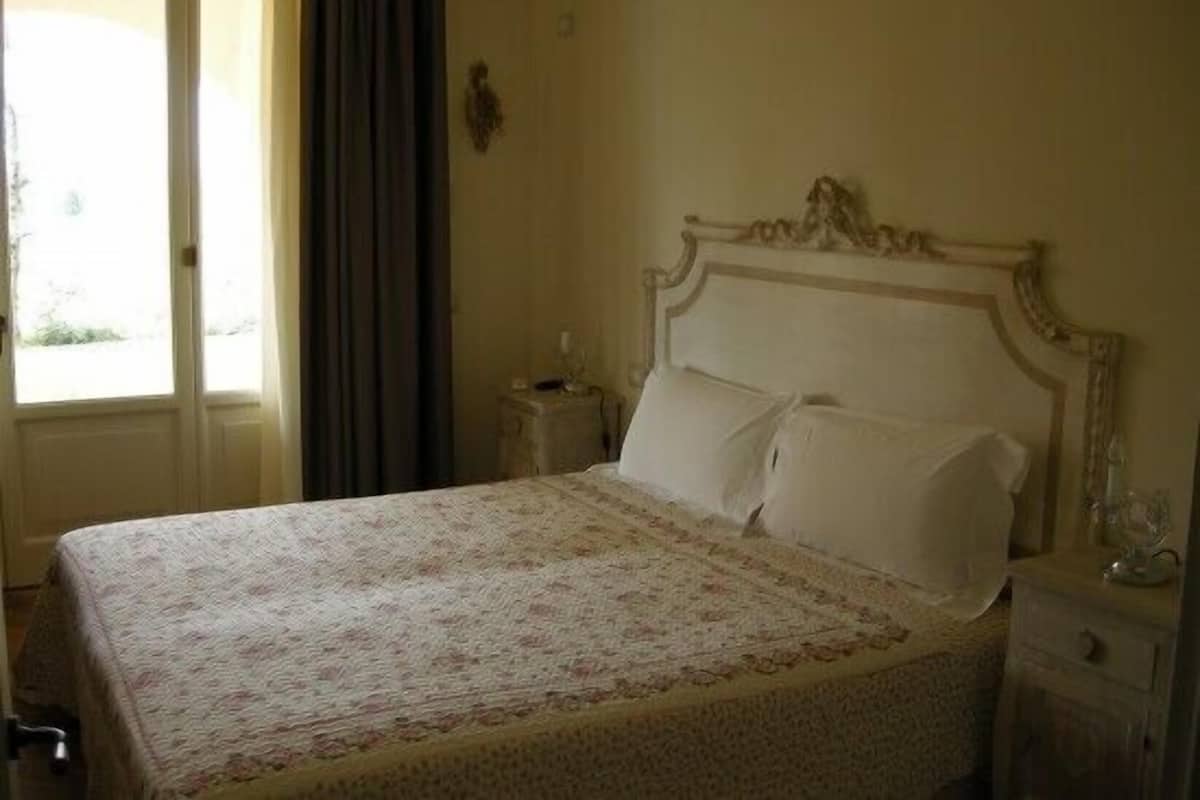 Un dormitorio con cama, mesita de noche, cómoda y ventana con cortinas.