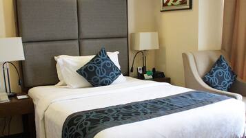 A hotel room with a large bed, two bedside tables, a chair, and a lamp.