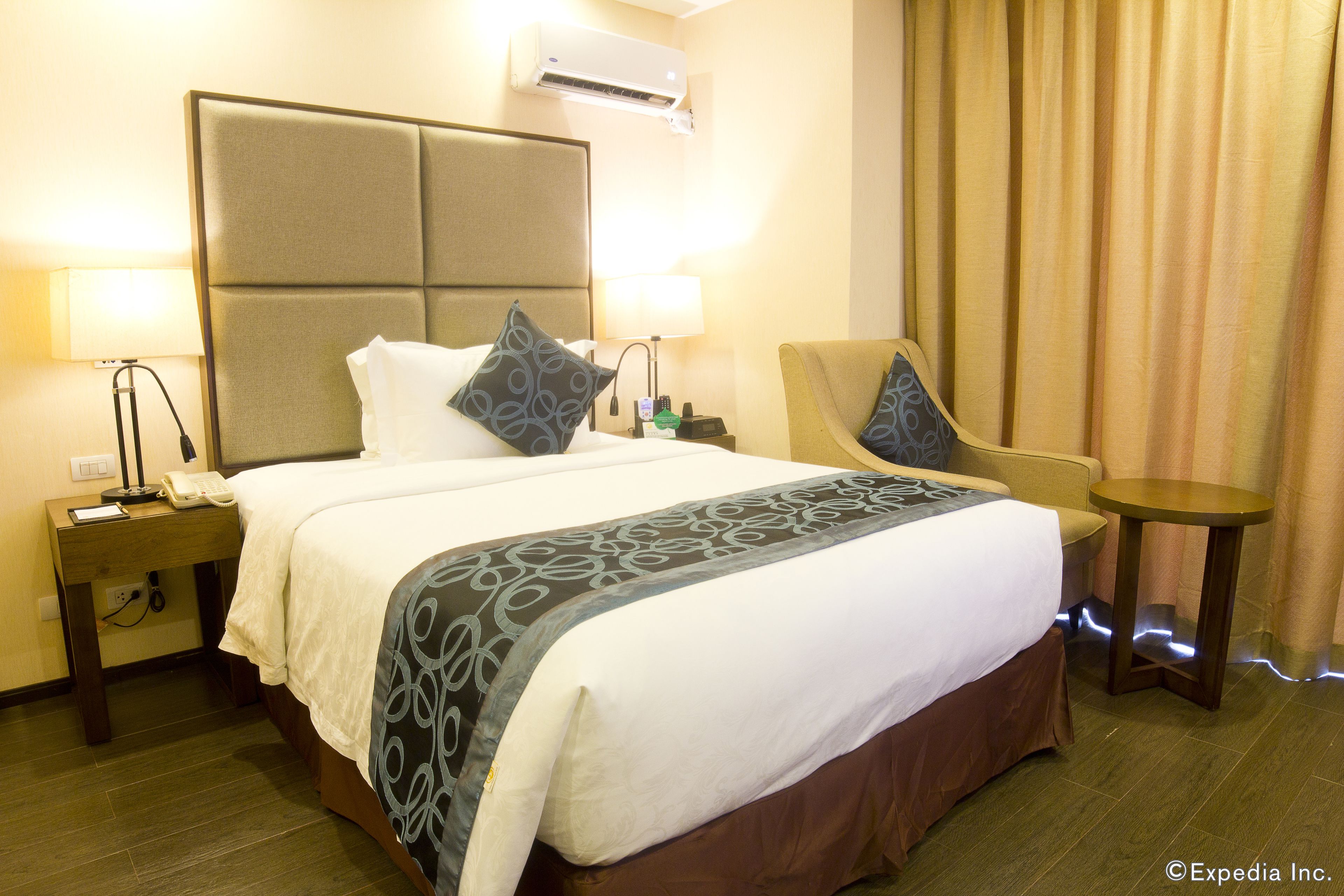 A hotel room with a large bed, two bedside tables, a chair, and a small table.