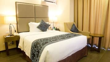 A hotel room with a large bed, two bedside tables, a chair, and a small table.