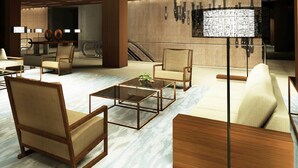 A modern lobby with wooden furniture, marble flooring, and a large floor lamp. - Golden Phoenix Hotel Manila (Pasay)