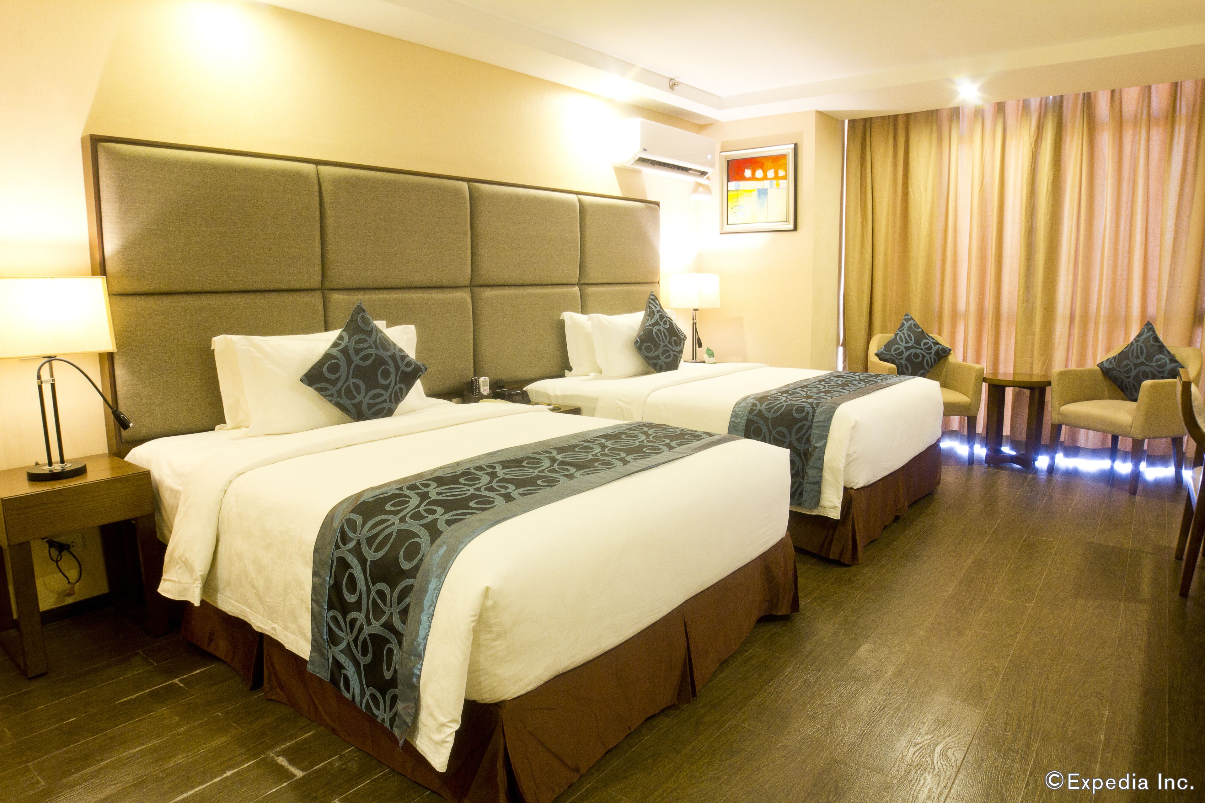 A hotel room with two beds, a desk, and a chair.