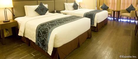 A hotel room with two beds, a desk, and a chair.
