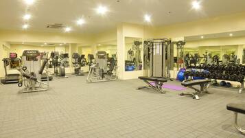 A gym with various exercise equipment, including treadmills, weight machines, and free weights.