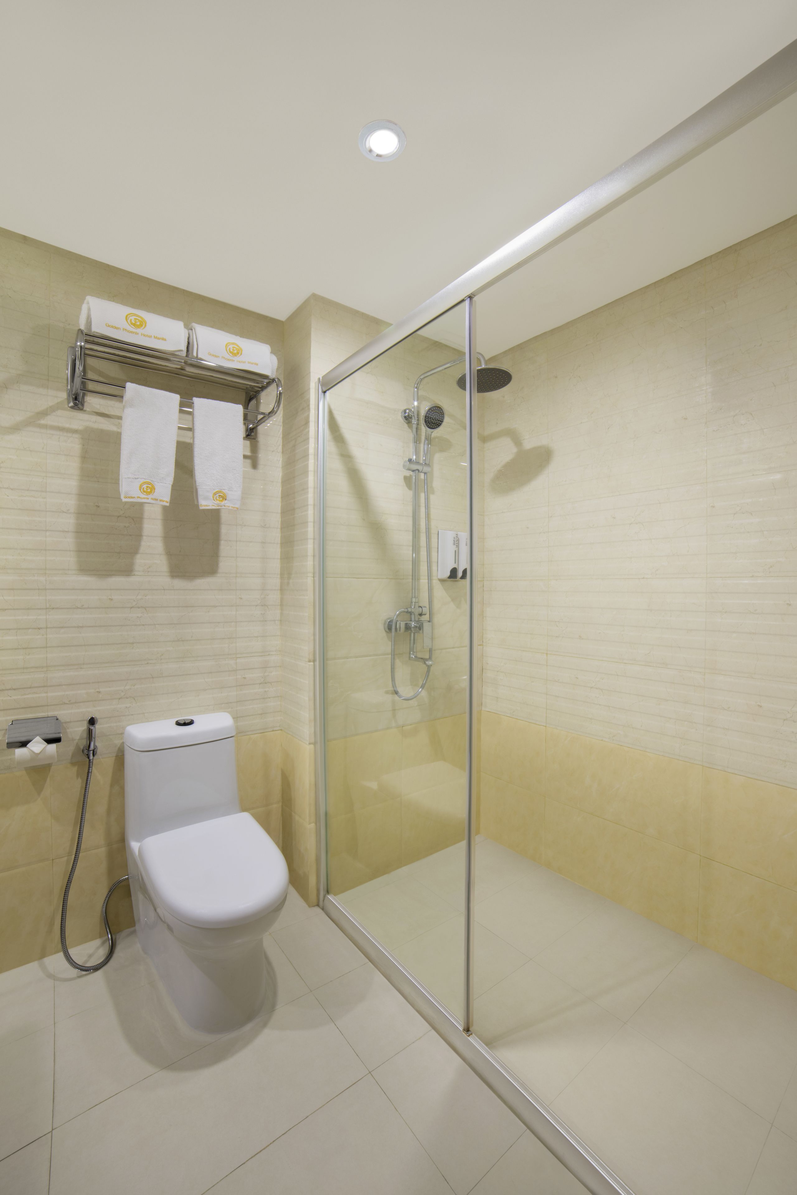 Een moderne badkamer met een douche met glazen wand, een toilet en een handdoekrek met handdoeken.