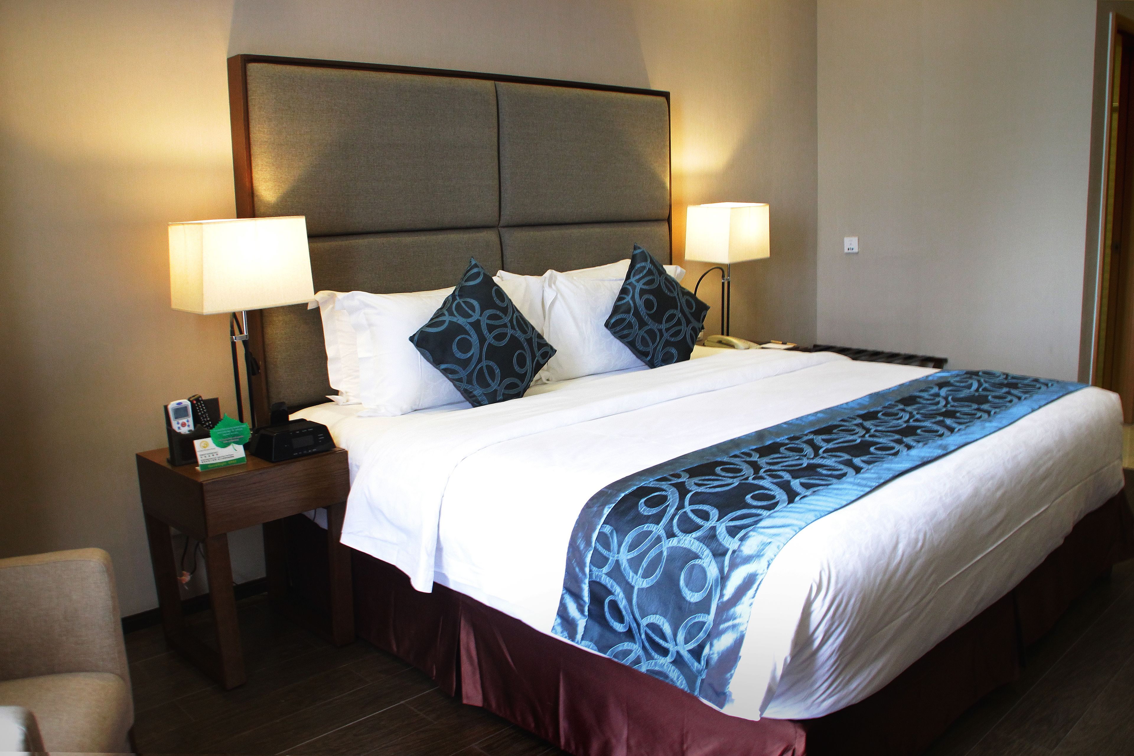 Habitación de hotel con una cama grande, dos mesitas de noche y una silla.