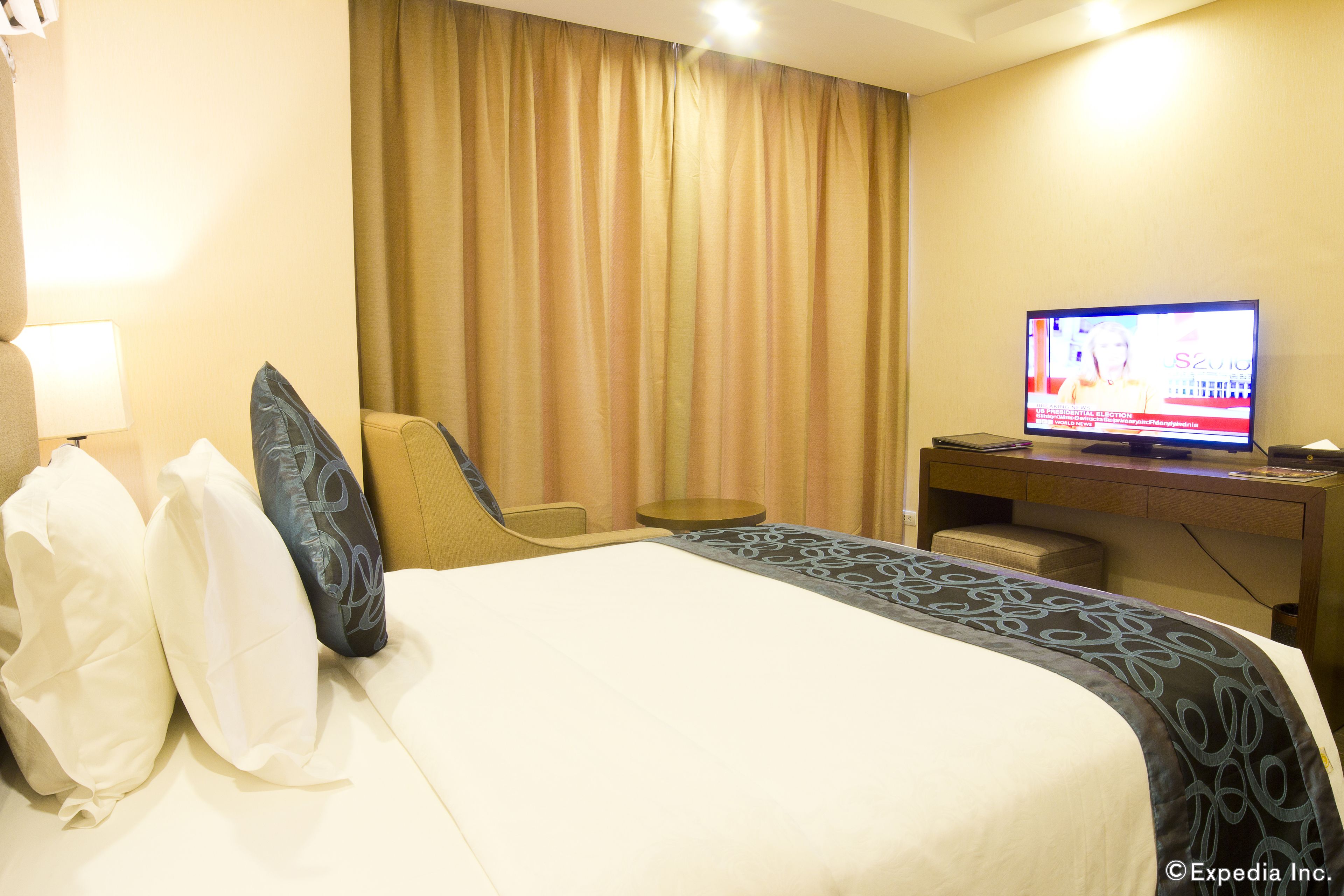 A hotel room with a bed, a television, a desk, and a chair.