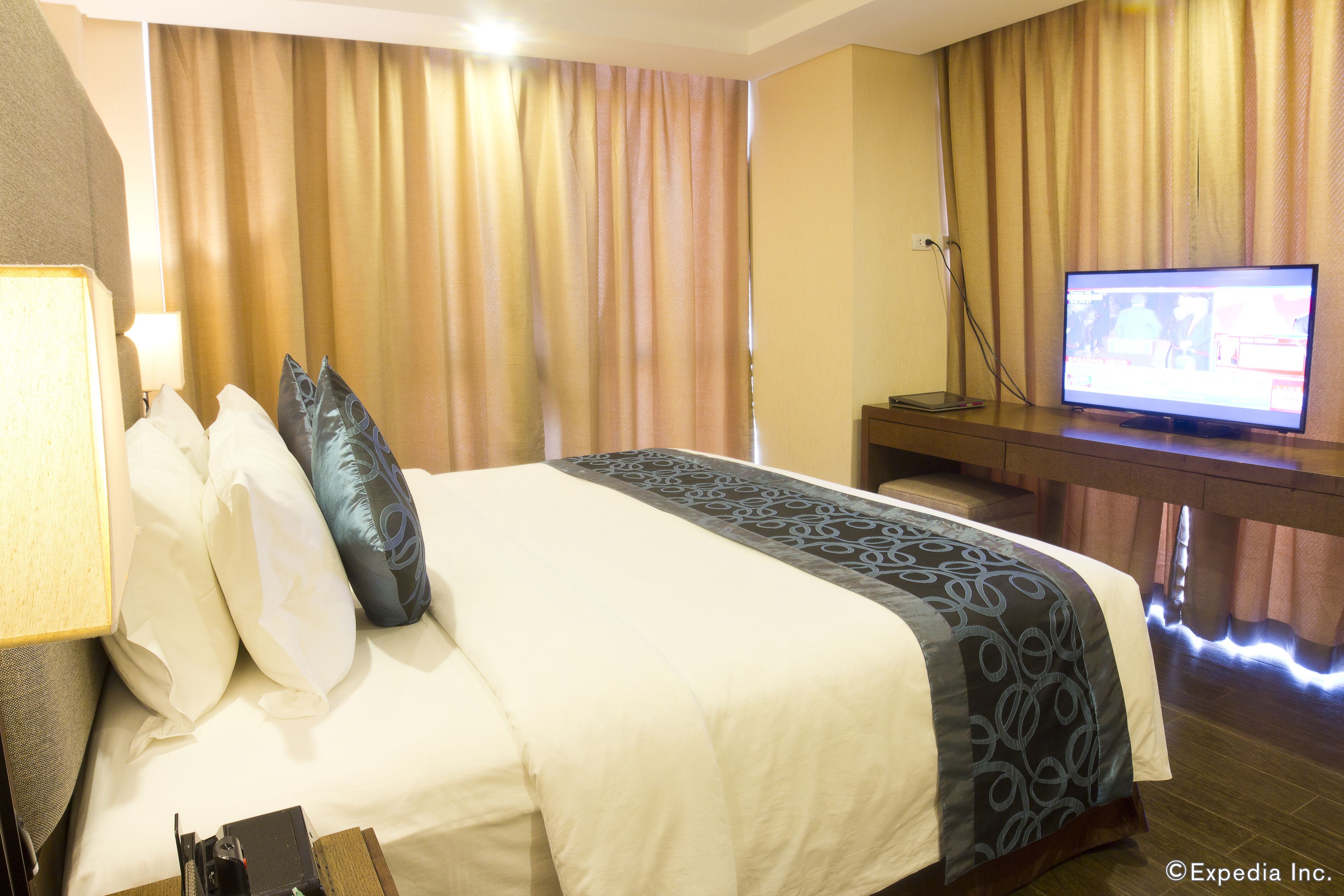 Una habitación de hotel con cama, televisión y escritorio.